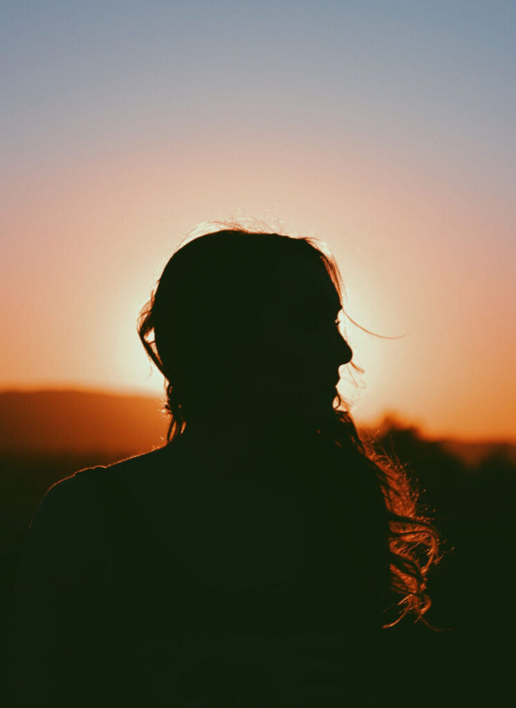 Frauensilhouette im untergehenden Sonnenlicht.